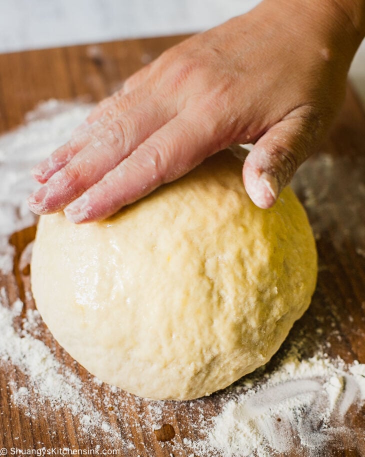 ha hand pressing down on a smooth dough ball