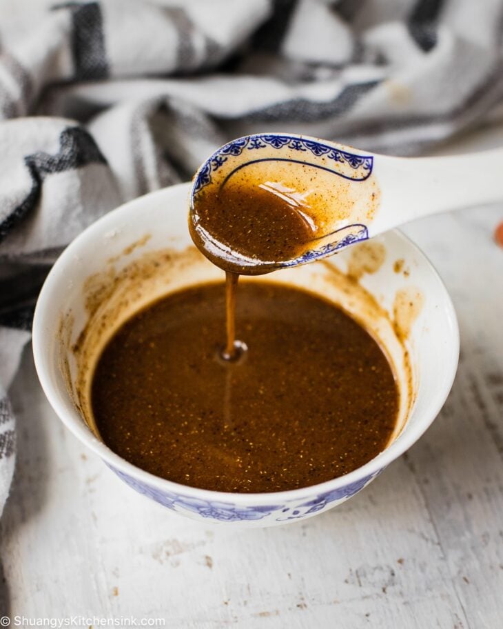 A spicy sauce in a bowl. A spoon is pouring the sauce into the bowl