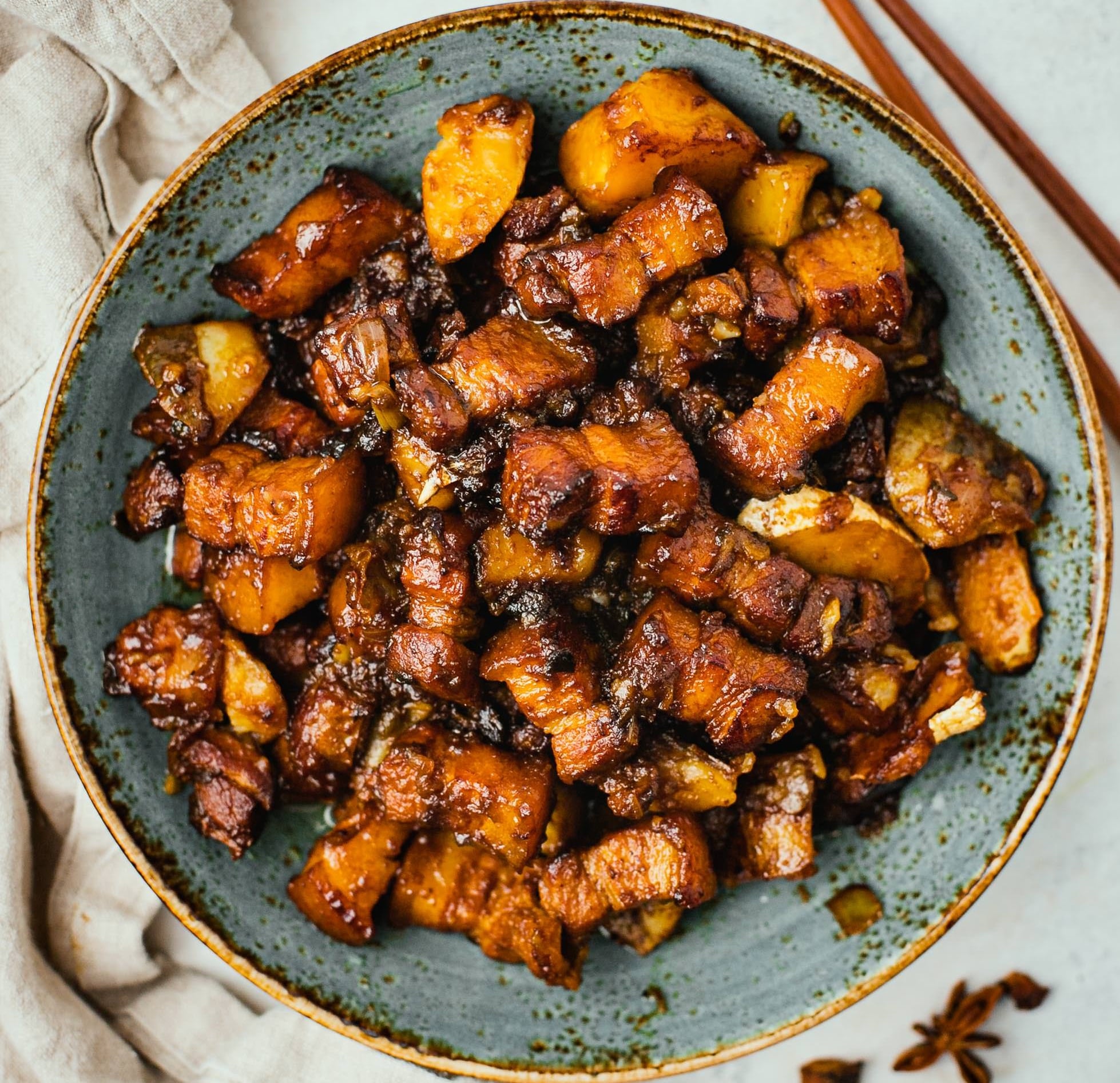 Juicy, caramelized pork belly coated in a glossy, sticky sauce—served on a blue plate.