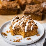 A piece of pumpkin coffee cake with a crumble topping drizzles with maple icing