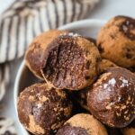 a bite is taken from a fudgy nut and chocolate ball topped with sea salt