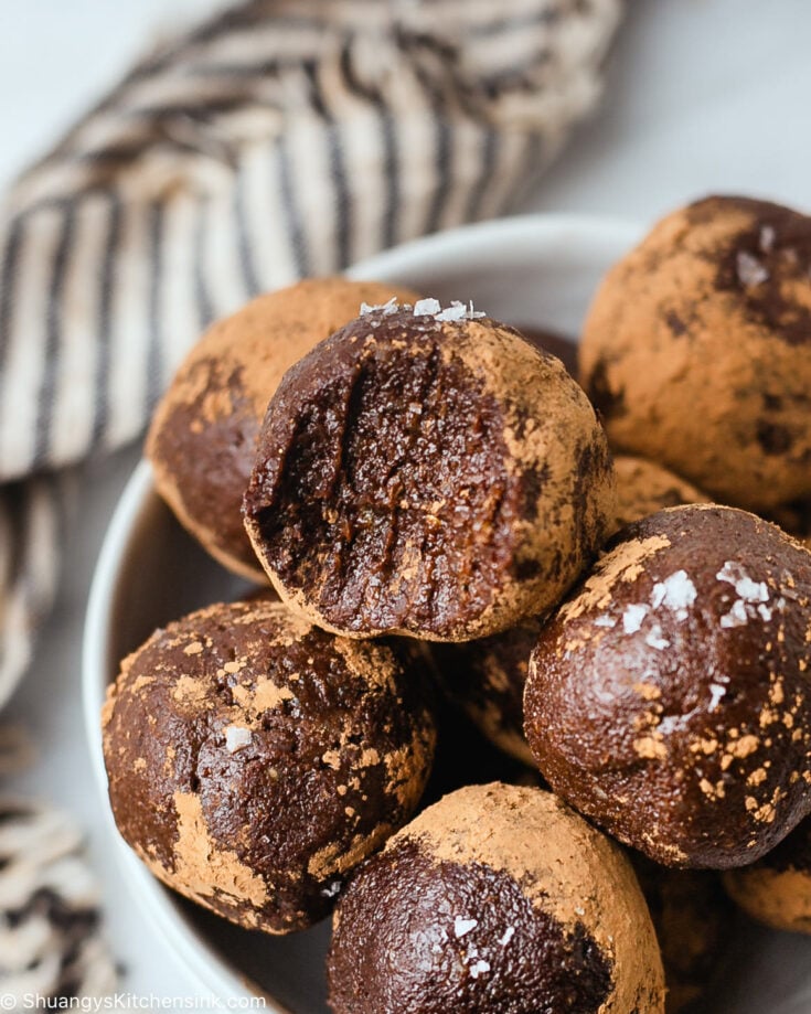 a bite is taken from a fudgy nut and chocolate ball topped with sea salt