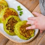 a baby hand is grabbing an edamame fritter, this is the perfect baby led weaning food