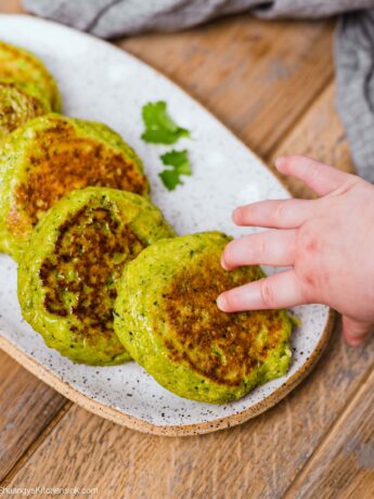 a baby hand is grabbing an edamame fritter, this is the perfect baby led weaning food