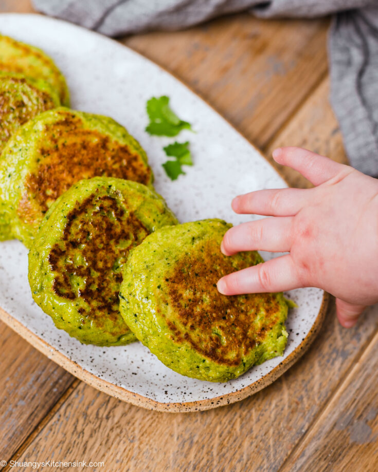 a baby hand is grabbing an edamame fritter, this is the perfect baby led weaning food