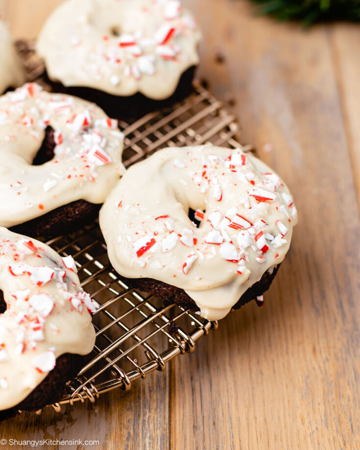 baked healthy chocolate donuts covered in a candy cane claze on a cooling rack