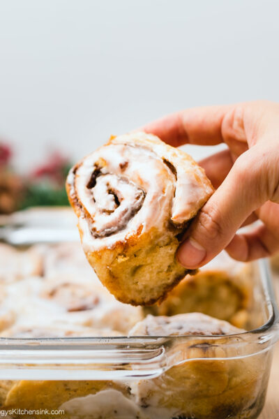 a hand is picking up a freshly baked vegan gingerbread roll iced with dairy-free icing