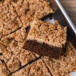 A freshly baked gluten free gingerbread cake cut into squares. It's topped with a gingerbread streusel.
