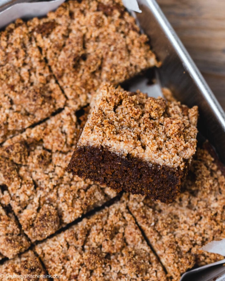 A freshly baked gluten free gingerbread cake cut into squares. It's topped with a gingerbread streusel.