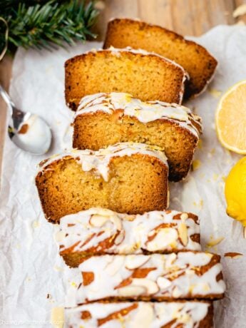 A loaf of soft and moist lemon almond cake topped with limoncello icing. There is a piece of lemon in the background.