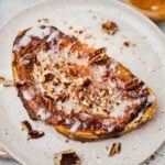 a piece of cinnamon roll custard toast on a cute plate. nuts have been sprinkled on top