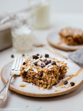 A plate with gluten free samoas baked oats topped with date syrup, coconut and vegan chocolate chips