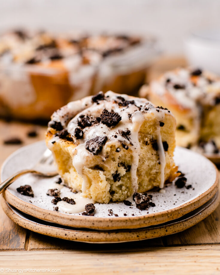 A fluffy cookies and cream cinnamon roll topped with vegan icing and crushed oreos