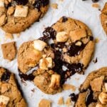 A piece of S'mores Cookie with graham cracker crust on the bottom, marshmallow and graham cracker on top. There is a bite in the middle.