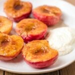 Air fried peaches are fully cooked and sitting on a plate waiting to be topped with the greek yogurt mixture
