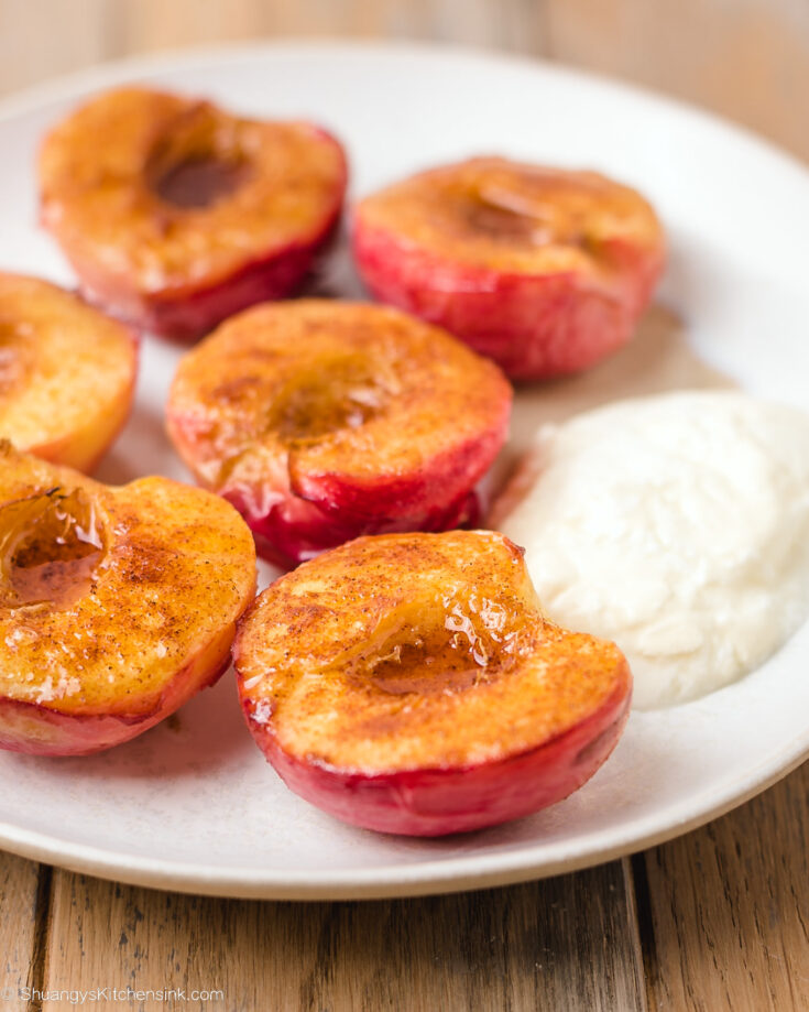 Air fried peaches are fully cooked and sitting on a plate waiting to be topped with the greek yogurt mixture