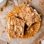 An Apple Crumb Muffin cut in half and you can see the fluffy texture and apples inside