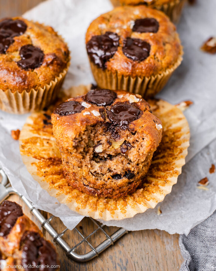 There is a muffin with a bite taken from it. It looks soft and moist and the banana muffin is paleo and gluten-free and topped with vegan chocolate chips
