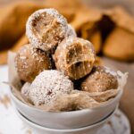 The image shows salted caramel energy bites with a bite taken out of them some have additional shredded coconut on them