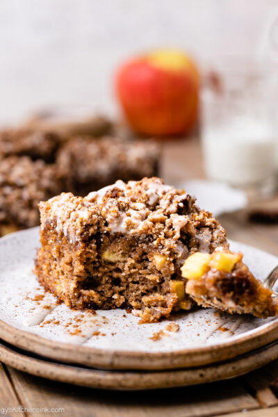 A piece of gluten free and paleo apple butter coffee cake that's moist and soft. It's topped with a sweet crumble streusel and a dairy-free icing