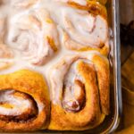 An 8x8 baking dish filled with freshly homemade pumpkin cinnamon tolls topped with easy vegan maple icing