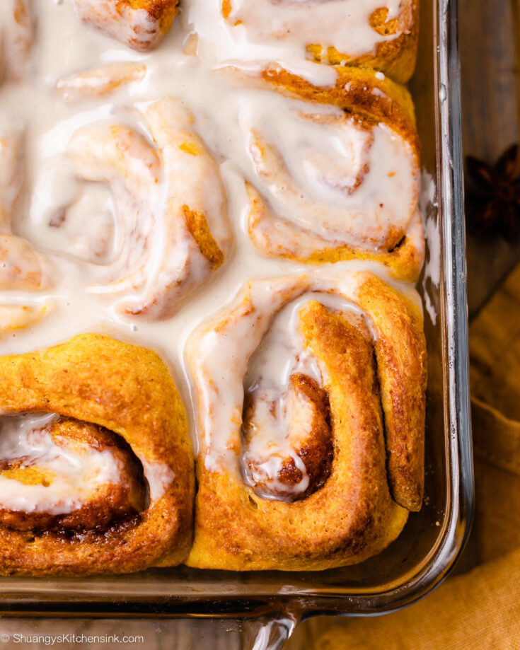 An 8x8 baking dish filled with freshly homemade pumpkin cinnamon tolls topped with easy vegan maple icing