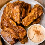 Air Fryer Pumpkin French Toast sticks served on a plate with a cream dipping sauce and drizzled with maple syrup