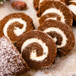 Gluten free gingerbread roll with vegan cream cheese frosting is being served perfectly sliced on parchment paper