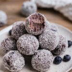 A plate of blueberry cheesecake balls covered in coconut shreds.