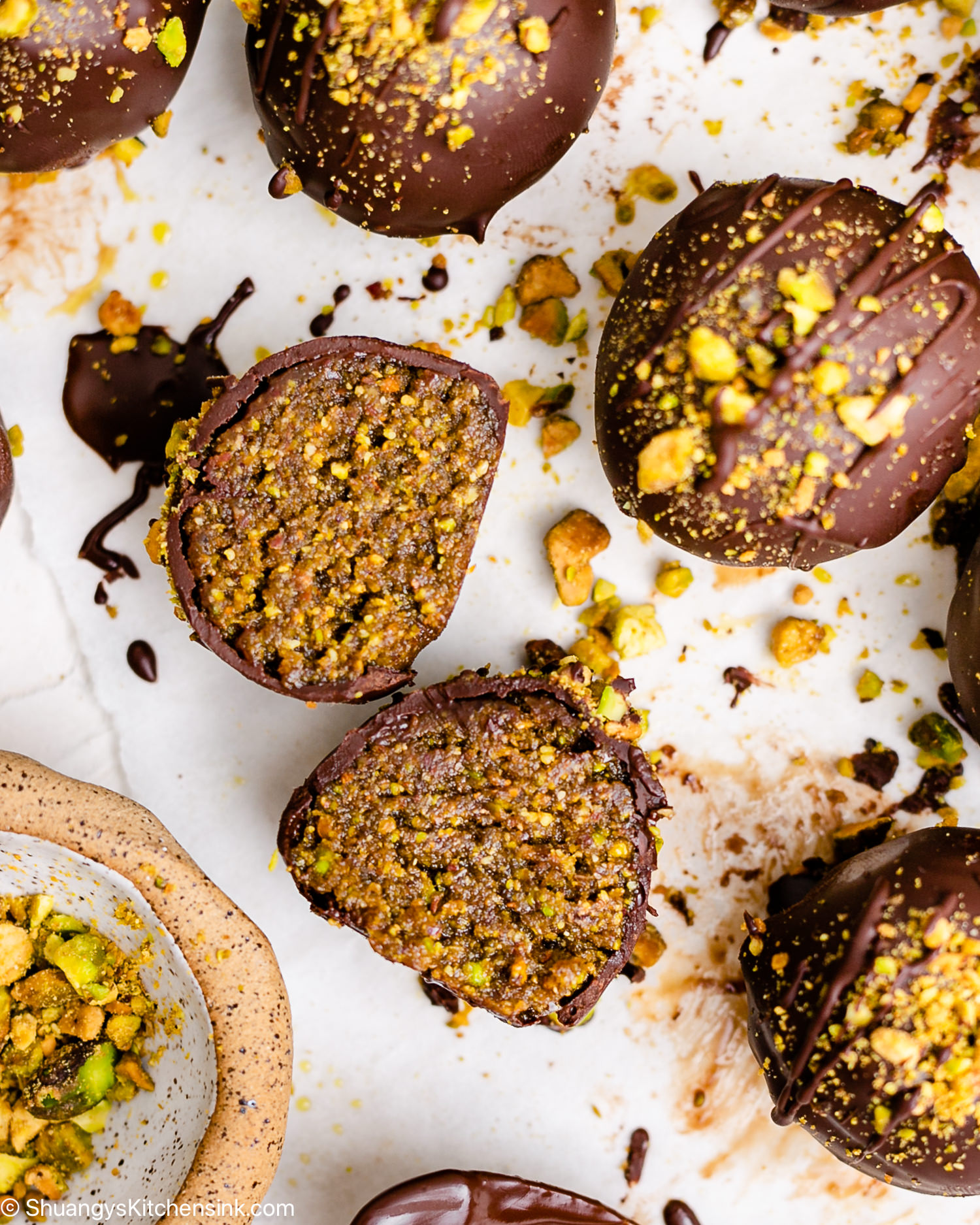 A chocolate coated pistachio truffle is cut in half.
