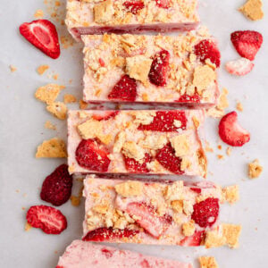 5 pieces of strawberry ice cream bars made with cottage cheese. There are some strawberry pieces and crushed graham crackers on top.