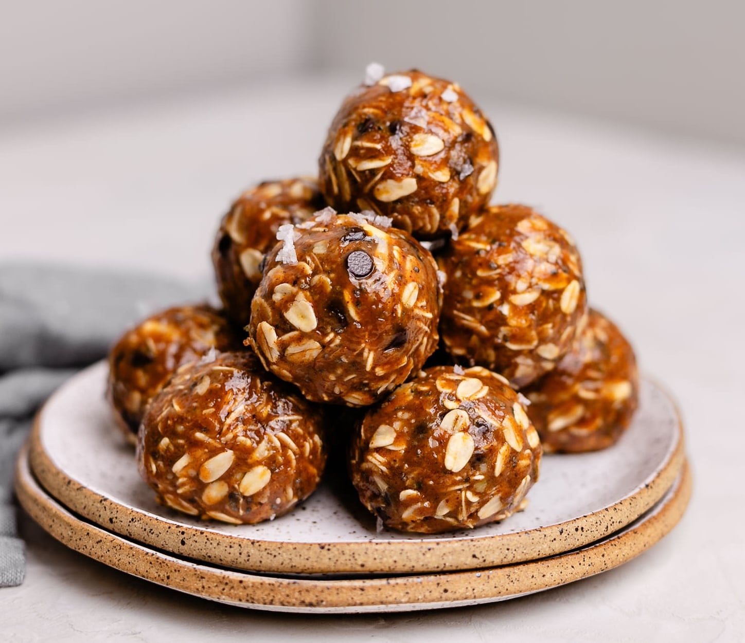 A plate of no bake almond butter protein balls with some flaky sea salt on top.