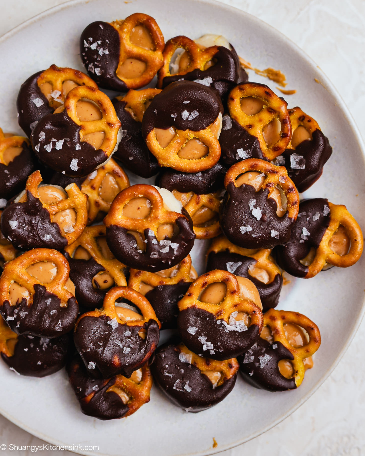 Frozen peanut butter banana bites made with banana slices, pretzels, creamy peanut butter, and a drizzle of melted dark chocolate, sprinkled with sea salt.