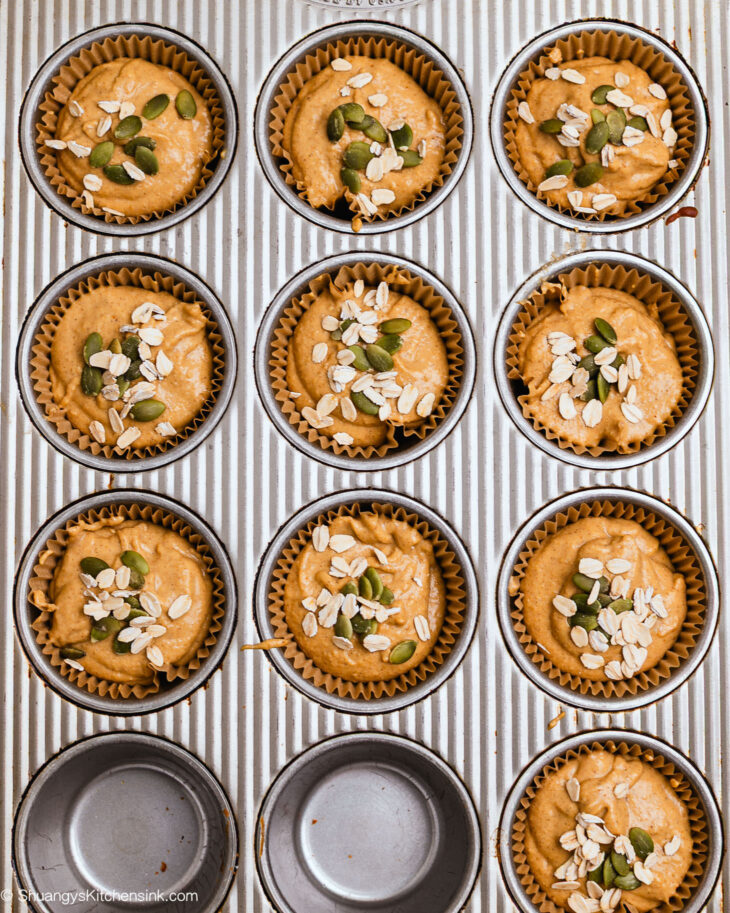 Muffin tin filled with ready to be baked pumpkin oat muffins