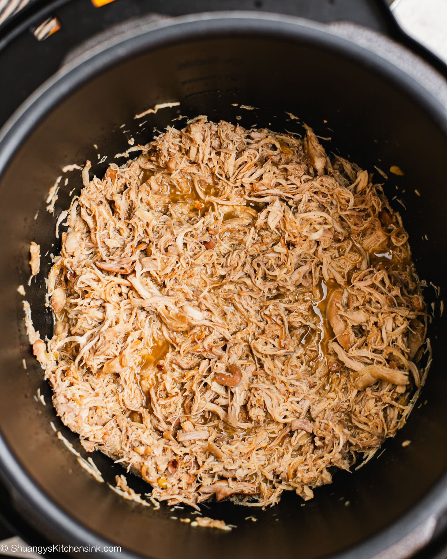 Shredded Asian-style pulled chicken in an Instant Pot, cooked until tender and coated in a savory honey garlic sauce.