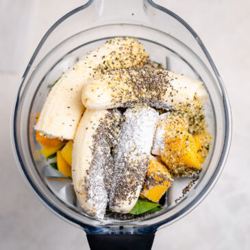 Bananas, mango, spinach, milk, chia seeds, and hemp seeds layered in a blender before blending into a healthy kids green smoothie.