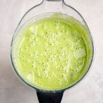 Top view of a creamy kids green smoothie with spinach and fruit blended until smooth and frothy in a high-speed blender.