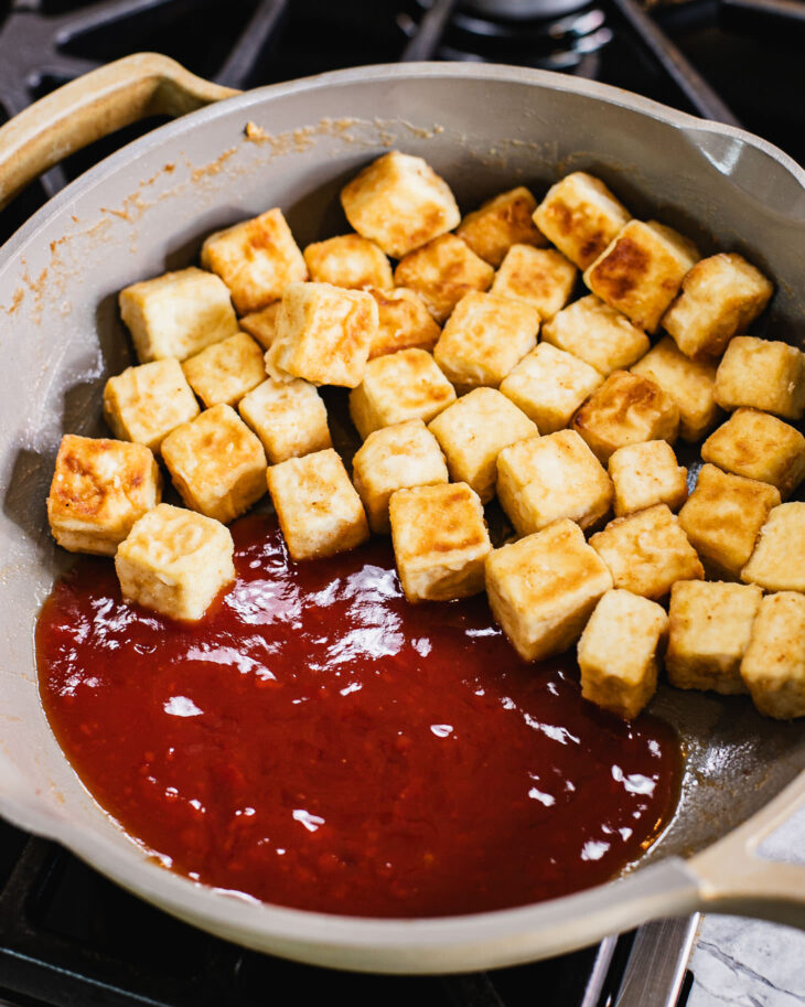 Instruction on how to make sweet and sour tofu - Push the tofu to one side fo the pan and pour the sauce on the other side.