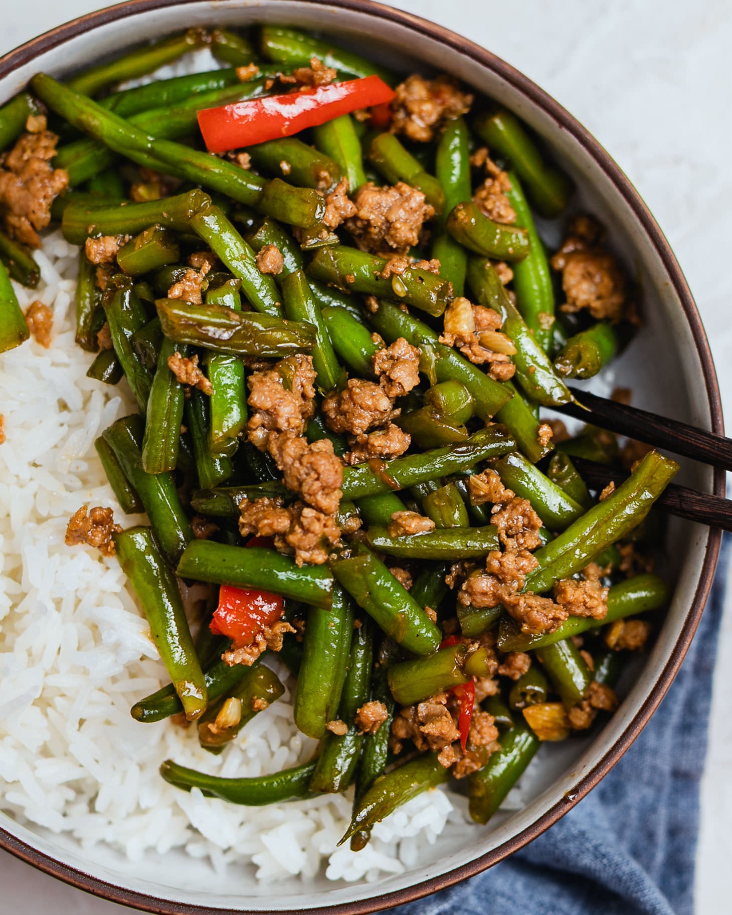 Stir fry green beans with pork mince served over jasmine rice in a bowl