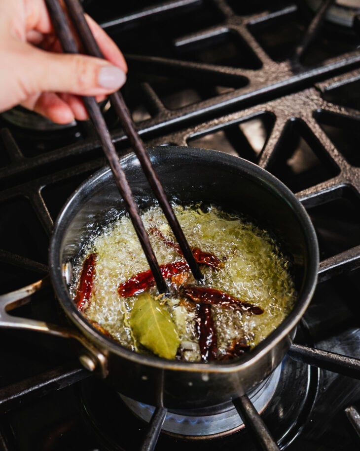 Bring everything to a gentle boil, then reduce the heat to medium-low and allow the aromatics and spices to slowly infuse the oil.