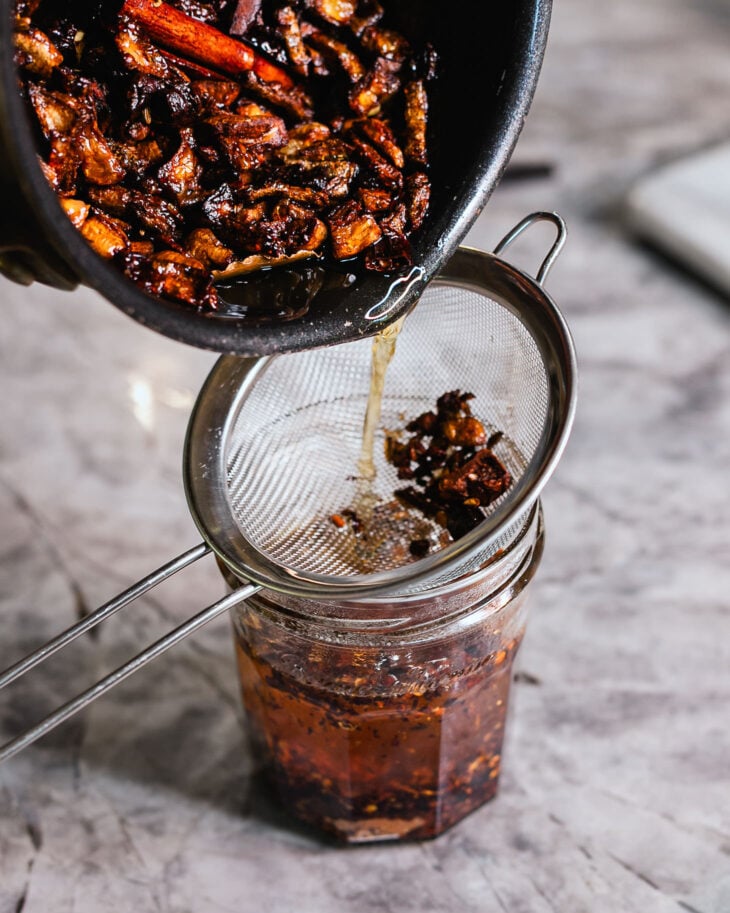 Once the aromatics are crispy, carefully strain the hot oil into the jar. 