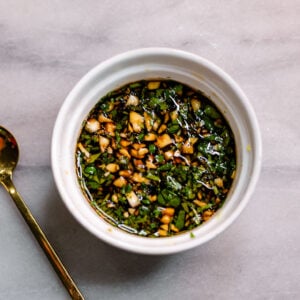 Homemade Chinese dumpling dipping sauce made with garlic, cilantro, soy sauce, Chinese black vinegar, and sesame oil in a white bowl.