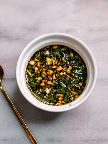 Homemade Chinese dumpling dipping sauce made with garlic, cilantro, soy sauce, Chinese black vinegar, and sesame oil in a white bowl.