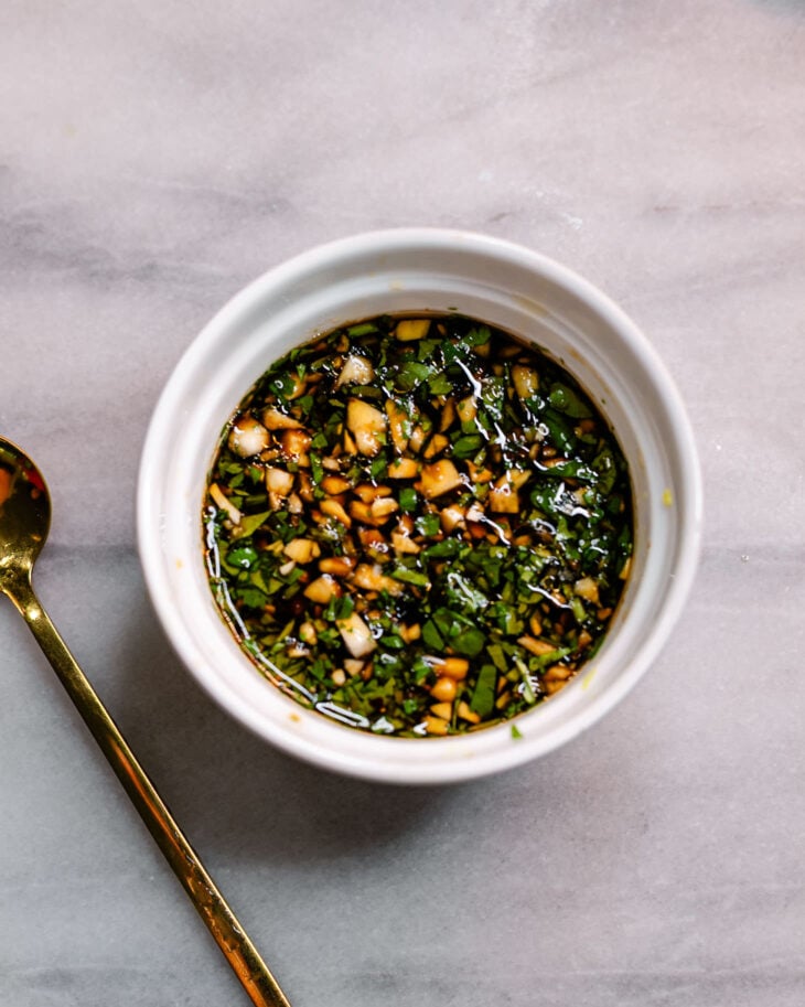 Homemade Chinese dumpling dipping sauce made with garlic, cilantro, soy sauce, Chinese black vinegar, and sesame oil in a white bowl.