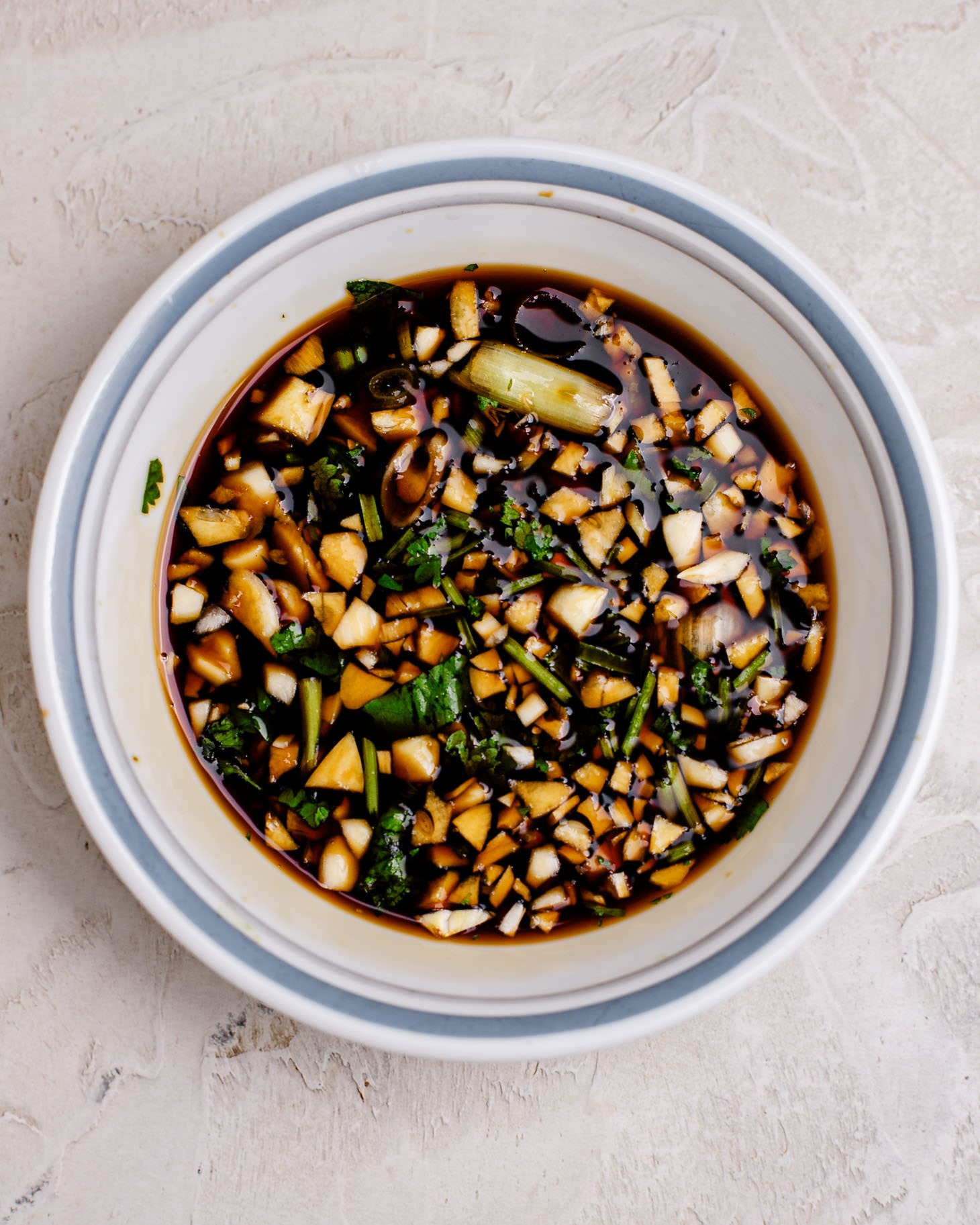 The combined all purpose Chinese marinade. In a bowl there is coconut aminos, Shaoxing wine, honey, minced garlic, cilantro and green onion.