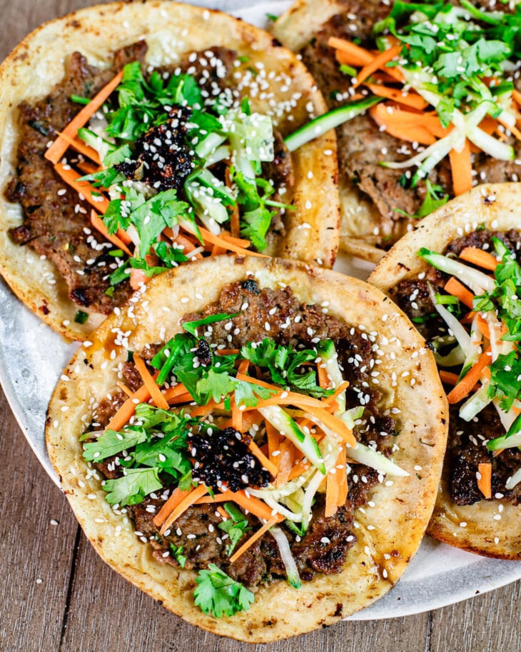 Dumpling filling smashed tacos topped with fresh cilantro, carrots, cucumbers and sesame seeds.