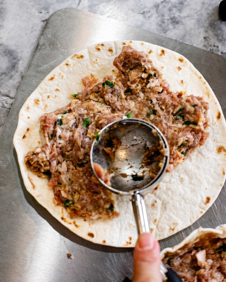 Spread a scoop of dumpling filling evenly over each tortilla, leaving a small border around the edges.