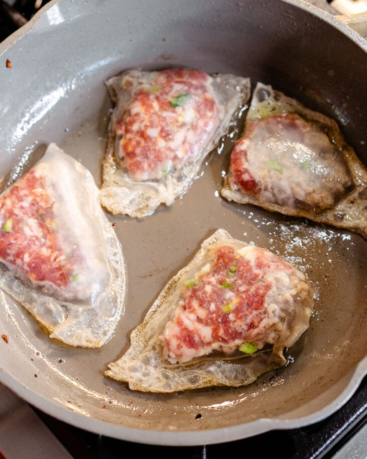 The edges of the rice paper dumplings appear to be crispy while the filling is half cooked.
