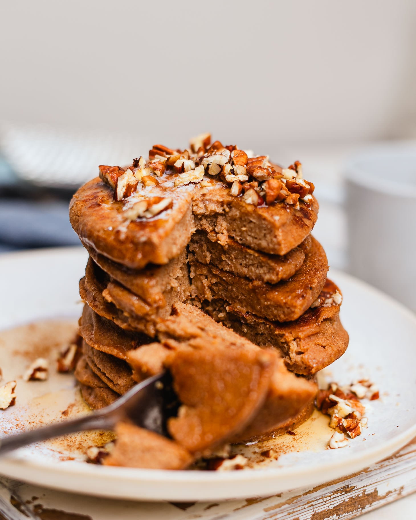 Stack of apple butter pancakes topped with chopped pecans and syrup