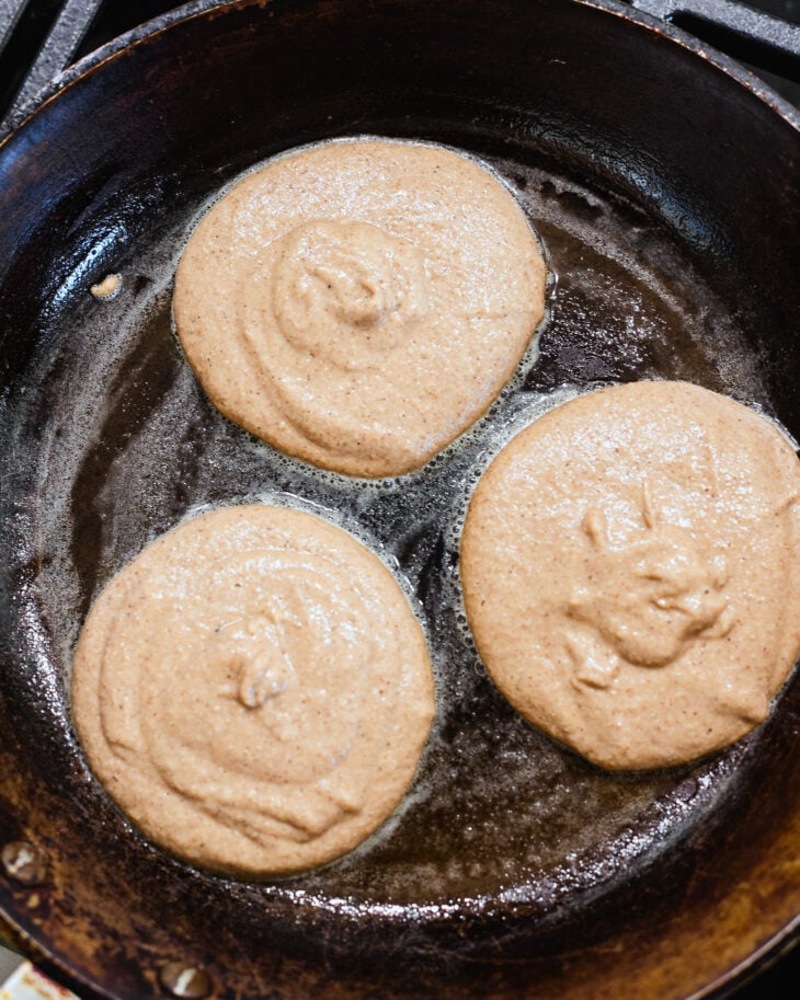 Apple butter pancake batter scooped into a greased cast iron skillet